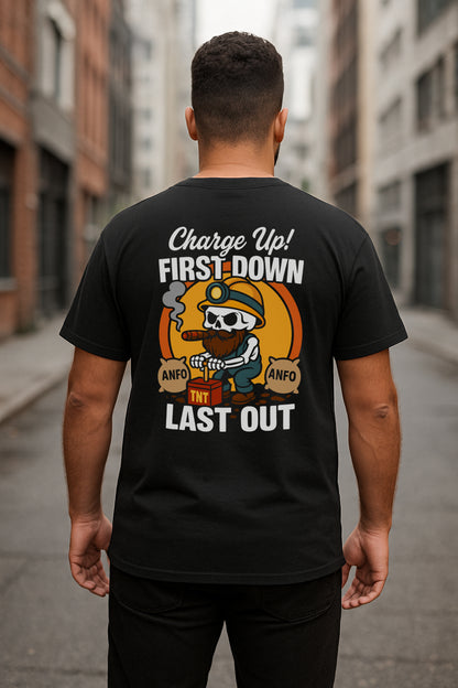 Person wearing a black t-shirt with a graphic design and text on the back, standing on an urban street.